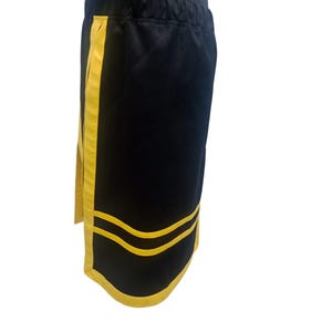 K&ouml;nnte beinhalten: Schwarze Sporthose mit gelben Streifen an den Seiten und am unteren Saum. Die Hose hat einen elastischen Bund. Die Hose ist aus einem weichen, leichten Material gefertigt.