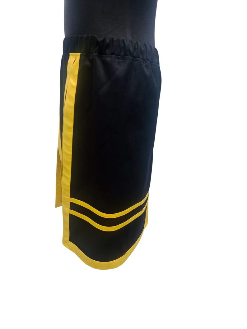 K&ouml;nnte beinhalten: Schwarze Sporthose mit gelben Streifen an den Seiten und am unteren Saum. Die Hose hat einen elastischen Bund. Die Hose ist aus einem weichen, leichten Material gefertigt.