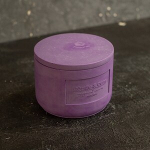 May include: Purple candle jar with a lid. The jar has a label that reads "Cozy & Chill" with the words "Natural Soy Wax" and "11.5 oz" below.