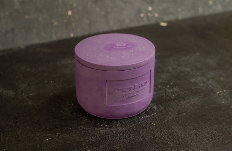 May include: Purple candle jar with a lid. The jar has a label that reads "Cozy & Chill" with the words "Natural Soy Wax" and "11.5 oz" below.
