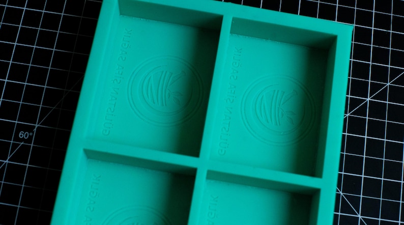 May include: A teal green silicone mold with four square compartments. Each compartment has a raised circular design with the text "Crazy 123 Crazy" embossed on the mold.