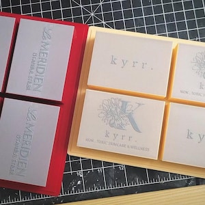 May include: Two sets of silicone molds for making soap bars. The first set is red and has four squares with the text "Le Meridien Istanbul Etles" embossed in silver. The second set is beige and has four squares with the text "kyrr. WOM. FOMC SKINCARE & WELLNESS" embossed in silver.