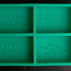 May include: Green silicone mold with four rectangular sections. Two sections have the text "DESIGN HKCRAFT" embossed in the mold. The other two sections have a floral design embossed in the mold.