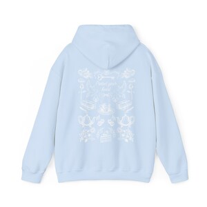 May include: Light blue hoodie with a white graphic print on the back. The graphic features a key, teacups, teapots, and flowers. The text "Protect your heart" is centered on the graphic.