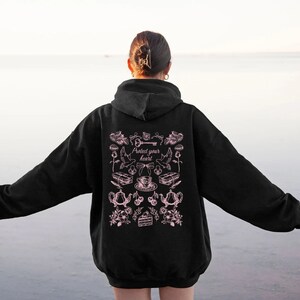 May include: Black hoodie with a pink graphic print on the back. The graphic features a key, a teacup, a cake, and other illustrations. The text "Protect your heart" is included in the graphic.