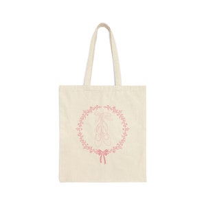 May include: A natural-coloured tote bag with a pink design of ballet shoes in a floral wreath.