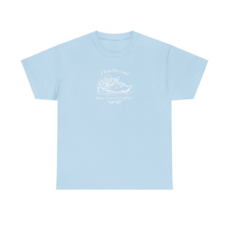May include: Light blue t-shirt with a white graphic of two swans and the text "I know love is real because I risked it all for it".