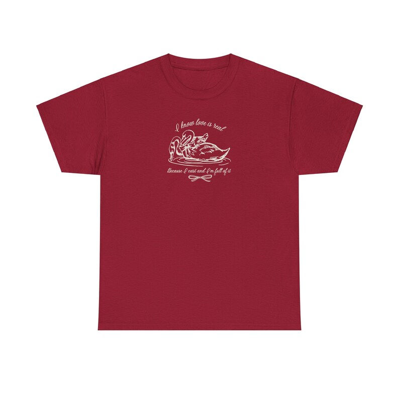 May include: Red t-shirt with a white graphic of two swans and the text "I know love is real because I exist and I'm full of it".