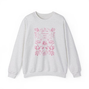 May include: A heather grey sweatshirt with a pink graphic design featuring a key, birds, teacups, and the text "Protect your heart".