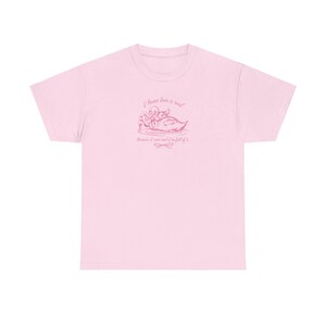 May include: Pink t-shirt with a pink graphic of two swans on a lake. The graphic says "I know love is real because I exist and I'm full of it".