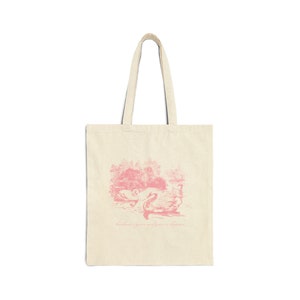 May include: A pink tote bag with a pink illustration of swans on a lake and the text "Kindness is grace and courage is kindness".