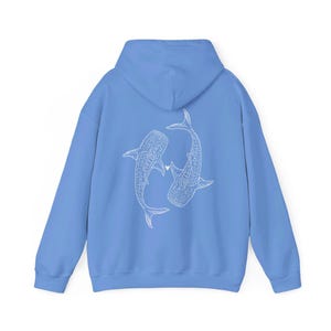 Puede incluir: Una sudadera azul claro con un contorno blanco de dos tiburones ballena que se miran con un peque&ntilde;o coraz&oacute;n entre ellos.