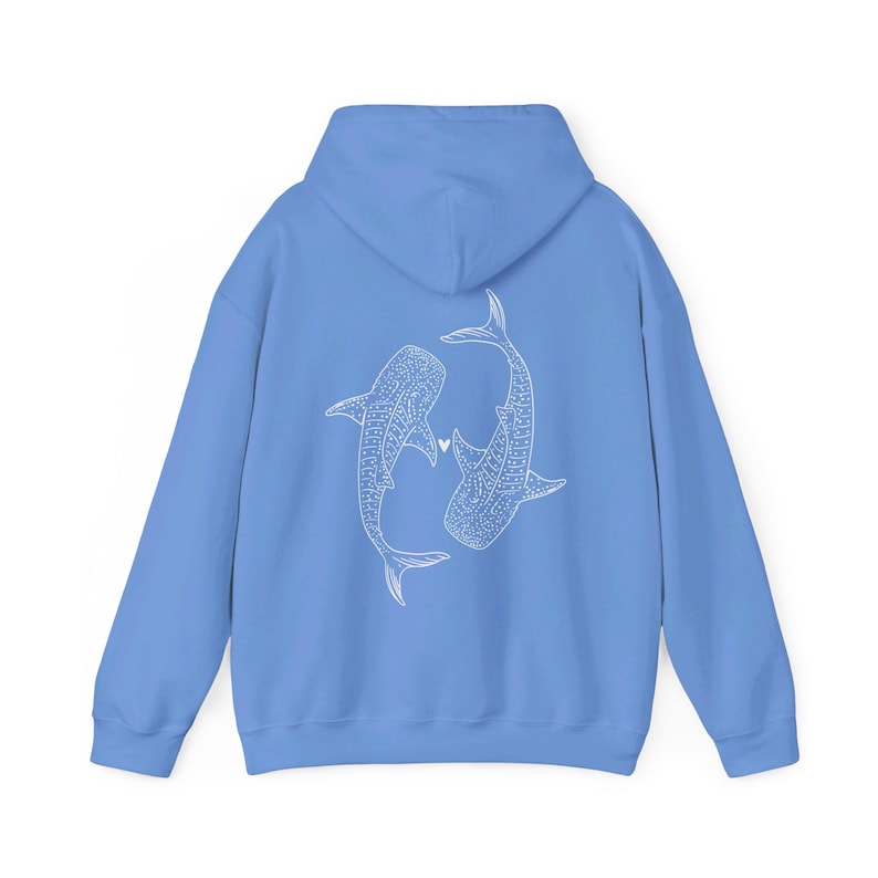 Puede incluir: Una sudadera azul claro con un contorno blanco de dos tiburones ballena que se miran con un peque&ntilde;o coraz&oacute;n entre ellos.