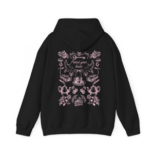 May include: Black hooded sweatshirt with a pink graphic print of a key, doves, teacups, cherries, and cake. The text "Protect your heart" is printed in pink on the sweatshirt.