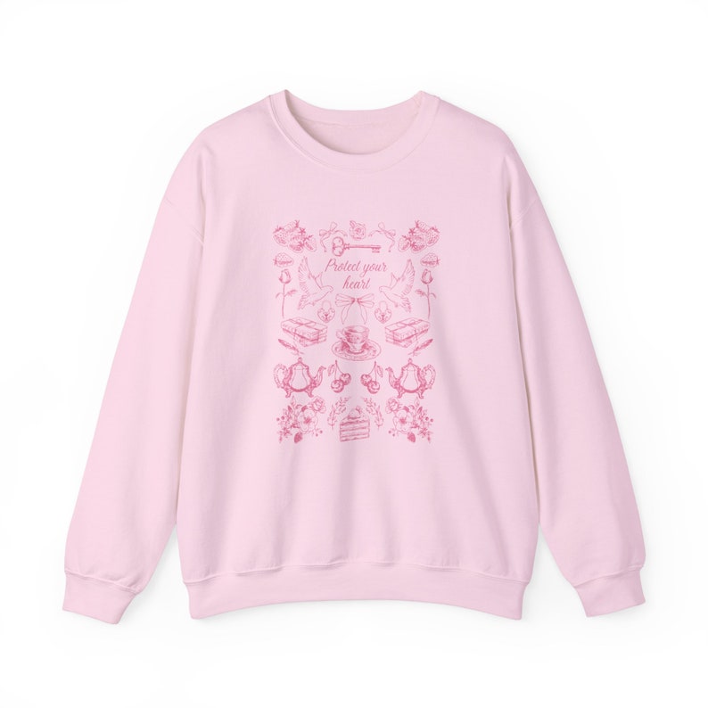 May include: A pink sweatshirt with a pink graphic print of a key, birds, teacups, and flowers. The text "Protect your heart" is printed on the sweatshirt.