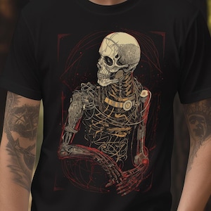 Può includere: T-shirt nero con un'illustrazione dettagliata di una figura scheletrica con elementi meccanici. Il design incorpora accenti rossi e dorati. L'opera d'arte ha uno stile vintage e anatomico, su sfondo scuro.