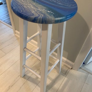 May include: White wooden bar stool with a blue and white marbled top.
