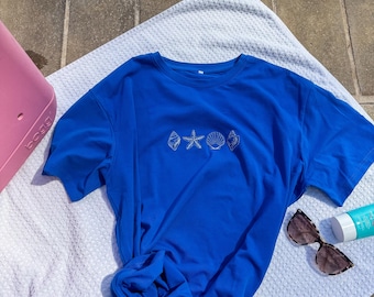 Camiseta oversized bordada com conchas do mar, azul praiano.