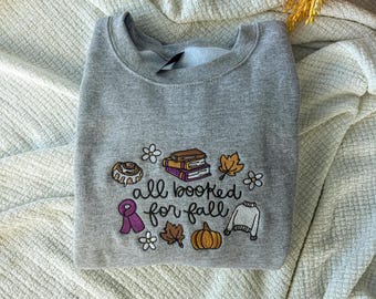 Moletom com gola redonda bordado "All Booked For Fall", ideal para amantes de livros no outono.