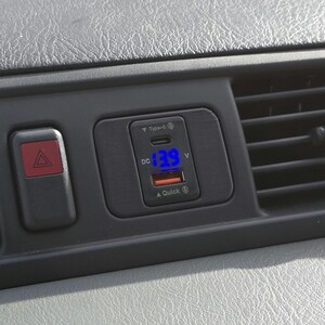 May include: A black car charger with a blue digital display showing "13.9 V". The charger has a USB-C port and a Quick Charge logo.