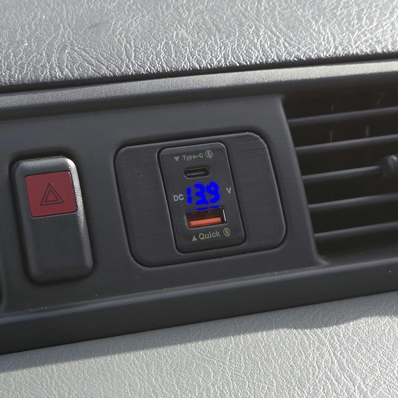 May include: A black car charger with a blue digital display showing "13.9 V". The charger has a USB-C port and a Quick Charge logo.