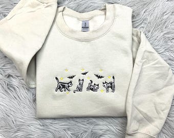 Puede incluir: Sudadera beige con un diseño bordado de cuatro gatos esqueleto negros, murciélagos y estrellas amarillas. La sudadera de cuello redondo está hecha de un material suave, ideal para Halloween o amantes de los gatos.