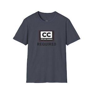 May include: A navy blue t-shirt featuring a graphic of a television screen with the letters "CC" inside, and the word "REQUIRED" below. The shirt is made of a soft material and has short sleeves.