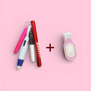 May include: A collection of pens and a small clip-on light against a pink background. The pens include pink, white, black, and red barrels. The clip-on light is white with a pink accent.