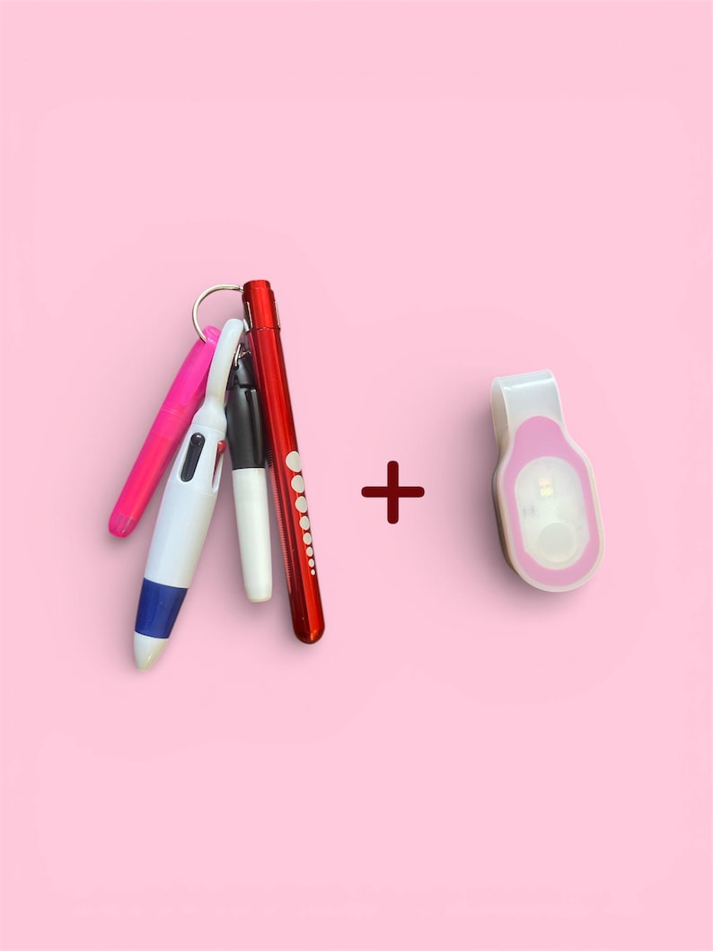 May include: A collection of pens and a small clip-on light against a pink background. The pens include pink, white, black, and red barrels. The clip-on light is white with a pink accent.