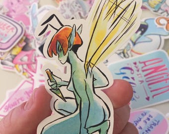 May include: A sticker featuring a watercolour illustration of a blue-green fairy with red hair and yellow wings holding a knife. The fairy is in a crouching position with its wings spread out behind it. The sticker has a white background and the artist's signature is in the bottom right corner.