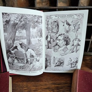 Puede incluir: Un libro abierto con ilustraciones de "Los papeles de Pickwick" de Charles Dickens. El libro presenta ilustraciones en blanco y negro de personas en varias escenas. El texto en la p&aacute;gina dice "Collins Clear-Type Edition of Dickens's Works."