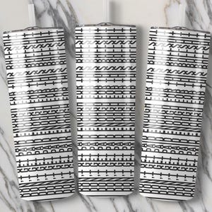 May include: Three white tumblers with a black geometric pattern and the text "ENOUGH FOR THIS BULLSHIT" are displayed. The tumblers have a straight design and a straw. The background is a marble pattern.