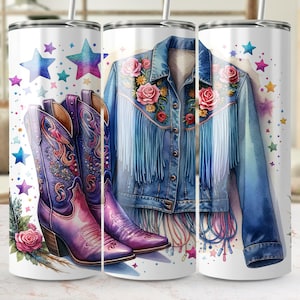 May include: A white tumbler featuring a watercolor design of purple cowboy boots, a denim jacket with floral embroidery and fringe, and colorful stars. The boots and jacket are the focal point of the design.