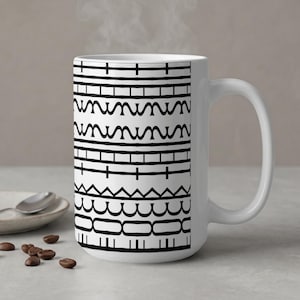 Puede incluir: Taza de café de cerámica blanca con un patrón geométrico negro. El diseño presenta líneas horizontales, formas onduladas y rectángulos. Sale vapor de la taza, lo que sugiere una bebida caliente. La taza tiene un asa grande.
