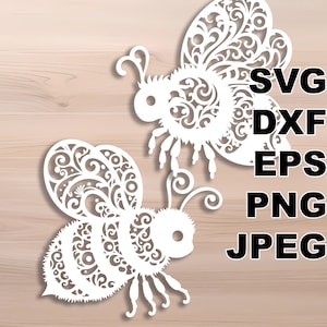 May include: Two white paper bees with intricate floral designs, cut out from paper. The bees are facing different directions and have a detailed pattern on their bodies.