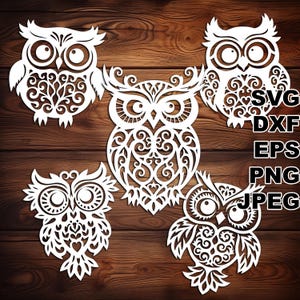 May include: Five white cutout paper owls with intricate designs. The owls are arranged in a semi-circle on a wood background.