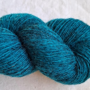 Op de afbeelding: Close-up van een streng teal-kleurig garen. Het garen is strak gewikkeld en toont de textuur van de vezels. De kleur is een diep, rijk teal, met subtiele kleurschakeringen. Ideaal voor brei- en haakprojecten.