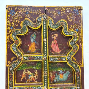 May include: A pair of intricately carved wooden doors with colourful painted scenes. The doors are decorated with floral motifs and feature scenes of people and animals. The doors are a beautiful example of traditional Indian craftsmanship.