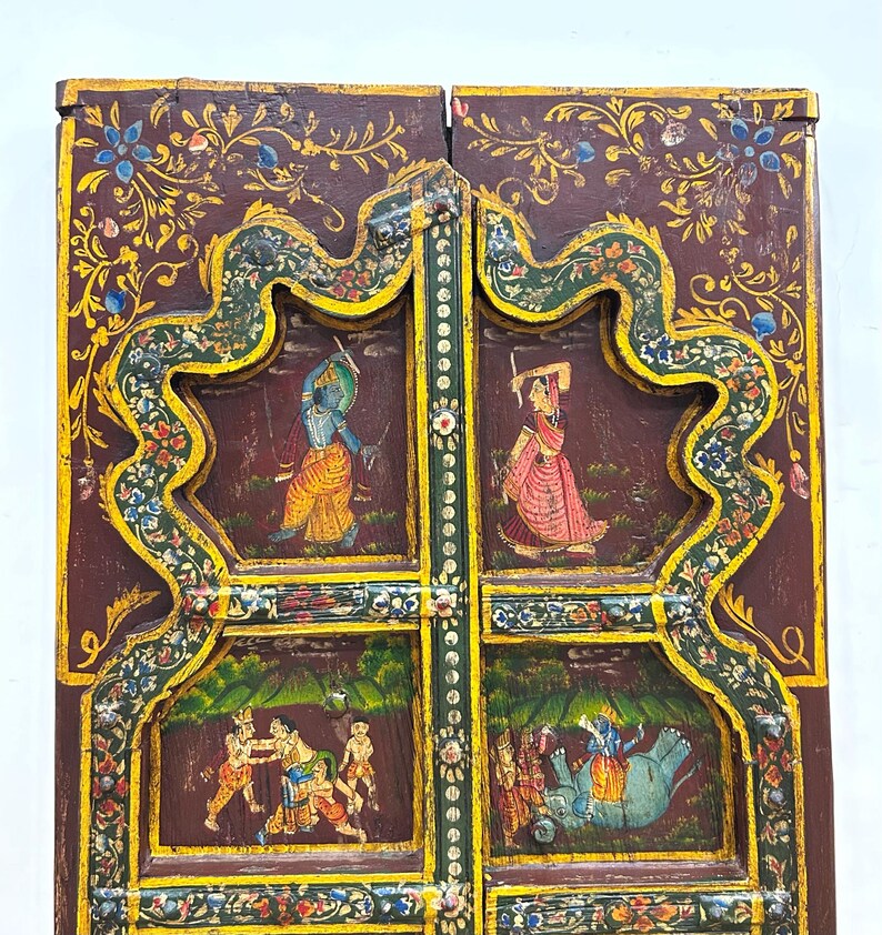 May include: A pair of intricately carved wooden doors with colourful painted scenes. The doors are decorated with floral motifs and feature scenes of people and animals. The doors are a beautiful example of traditional Indian craftsmanship.