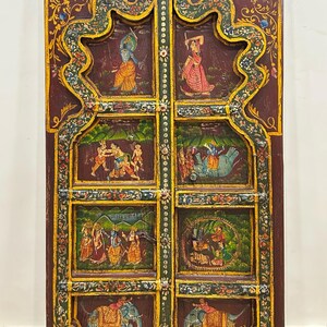 May include: A pair of wooden doors with intricate carvings and colourful paintings depicting scenes from Hindu mythology. The doors are painted in shades of red, green, blue, and gold.