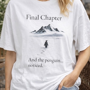 Może przedstawiać: Biała koszulka z napisem "Final Chapter" nad ilustracją gór i pingwinem idącym po śniegu. Poniżej ilustracji znajduje się napis "And the penguin... noticed".