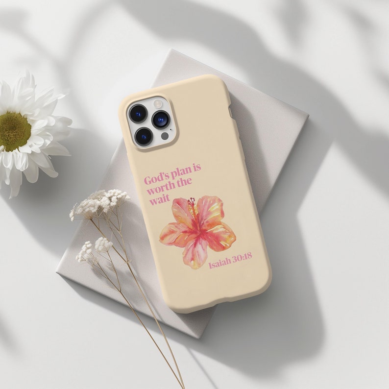May include: A cream-colored phone case with a pink flower and the text "God's plan is worth the wait Isaiah 30:18".