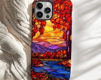 May include: A phone case featuring a stained-glass design of a landscape with a lake, trees, and mountains. The case has a vibrant color palette of red, orange, yellow, purple, and blue. The design resembles an autumn scene.