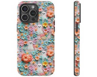 May include: A phone case featuring a 3D floral design with pastel colors. The case has a pink background with blue, orange, yellow, and purple flowers. Small white ghost figures are scattered throughout the design. The side view shows the same floral pattern.