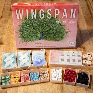 May include: A Wingspan board game set with a box featuring a peacock illustration and the text "Wingspan Asian Linnut - Lintuosa". The set includes game cards, dice, and wooden tokens.