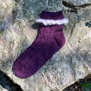 May include: Purple knitted socks with a white fluffy trim around the top of the sock.