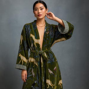 May include: A green velvet robe with a jungle-themed pattern featuring leopards, birds, and foliage. The robe has a tie waist, wide sleeves, and striped cuffs. The overall design is a luxurious and elegant garment.