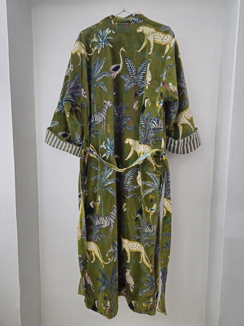 May include: A green velvet robe with a jungle print featuring zebras, leopards, and birds. The robe has a tie belt and long sleeves.