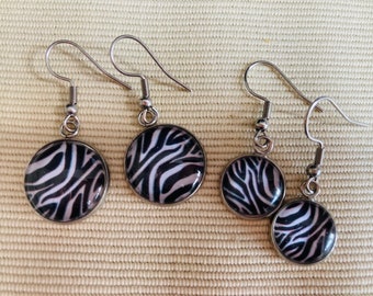 Peut inclure: Un ensemble de trois paires de boucles d'oreilles argentées avec des motifs zébrés noirs et blancs. Les boucles d'oreilles sont de tailles différentes.