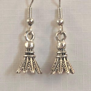 May include: A pair of silver-coloured earrings. Each earring features a decorative shuttlecock design with intricate feather detailing. The earrings have a hook closure for pierced ears.